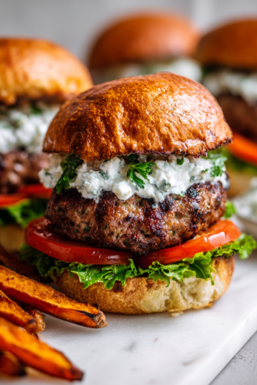 Savoureux burgers d'agneau à la marocaine, préparés au barbecue avec une sauce tzatziki fraîche. Parfait pour vos repas d'été
